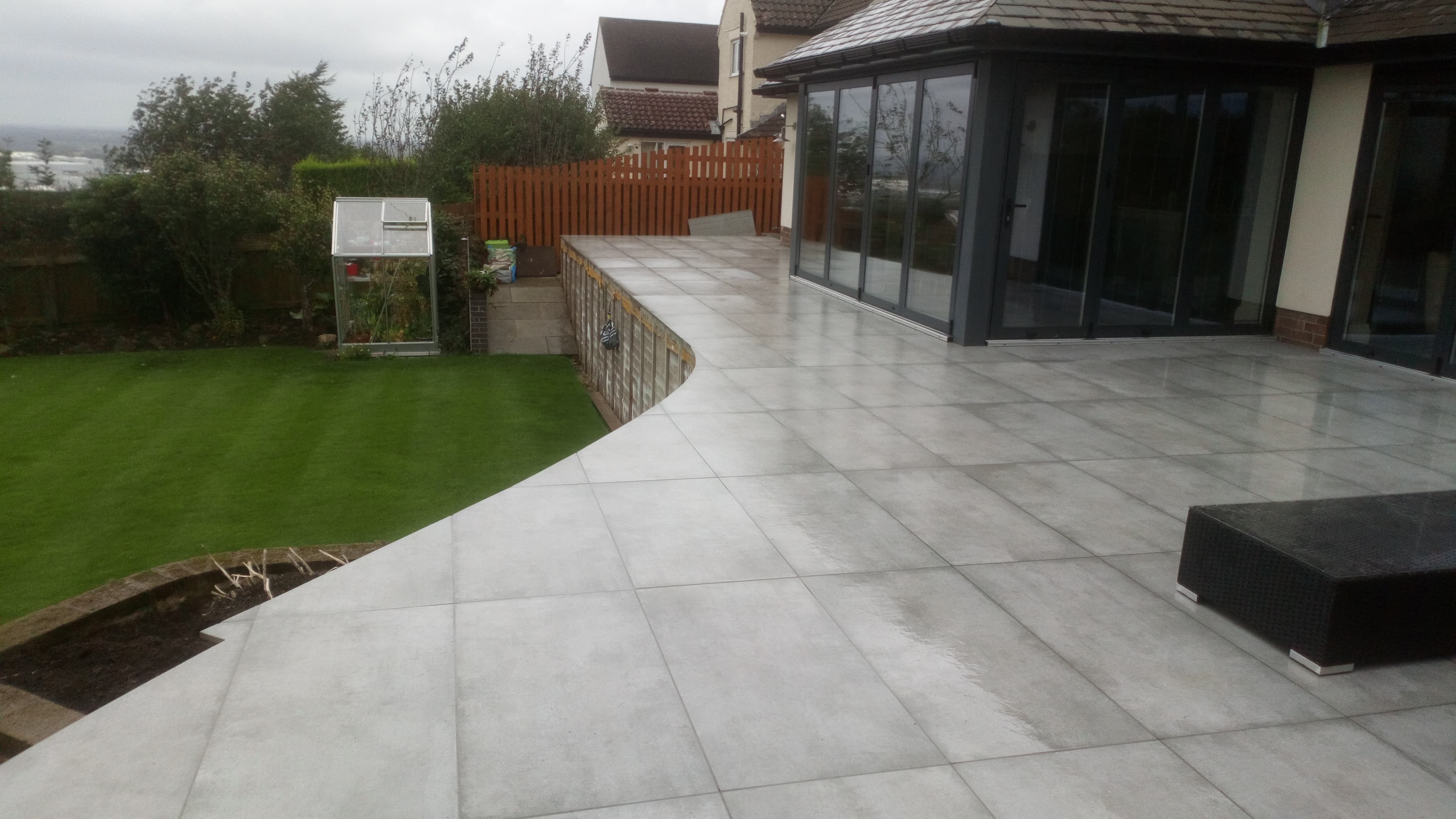 Sweeping curved large-format grey porcelain patio around a contemporary house
