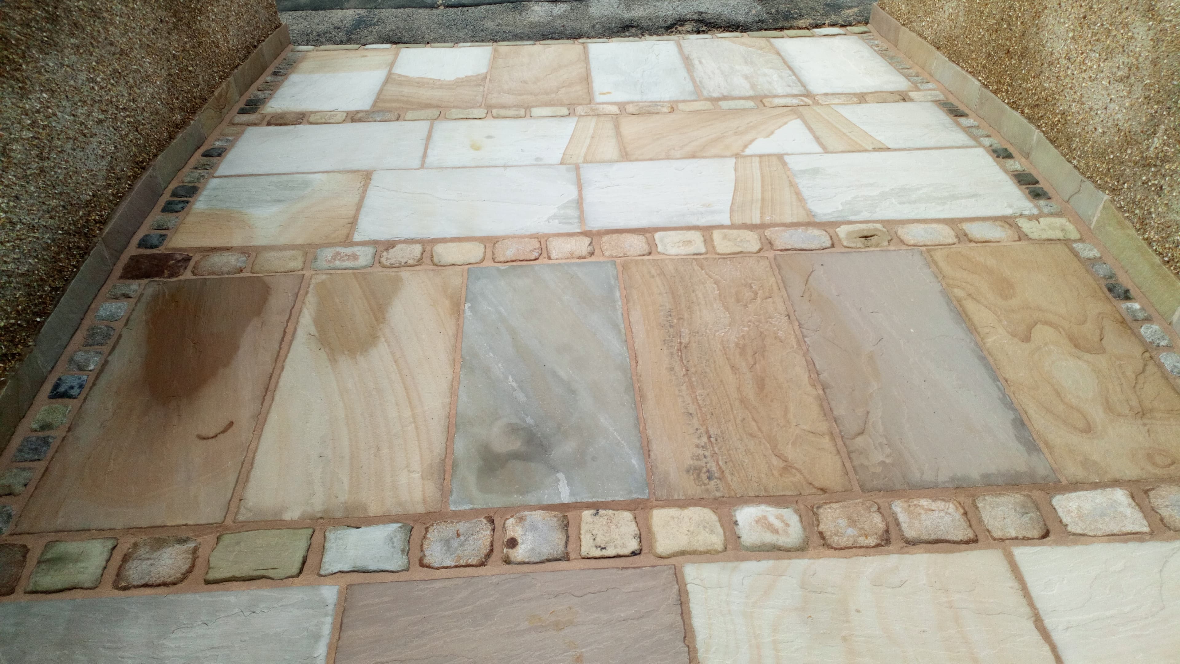 Multi-stone Indian sandstone patio with cobble border and inlay strip