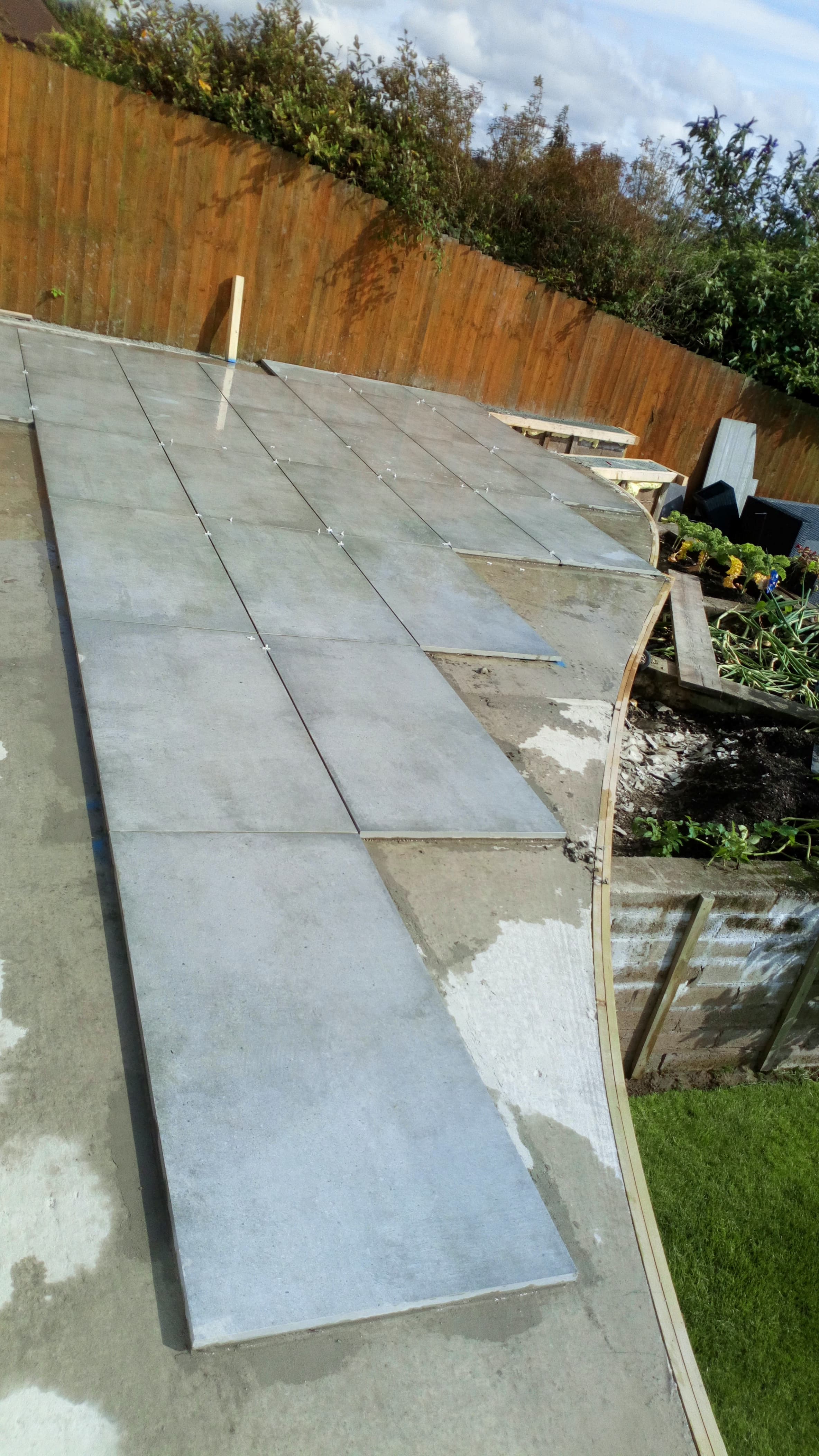 Curved porcelain patio mid-installation — large-format slabs being set with spacers along the sweep