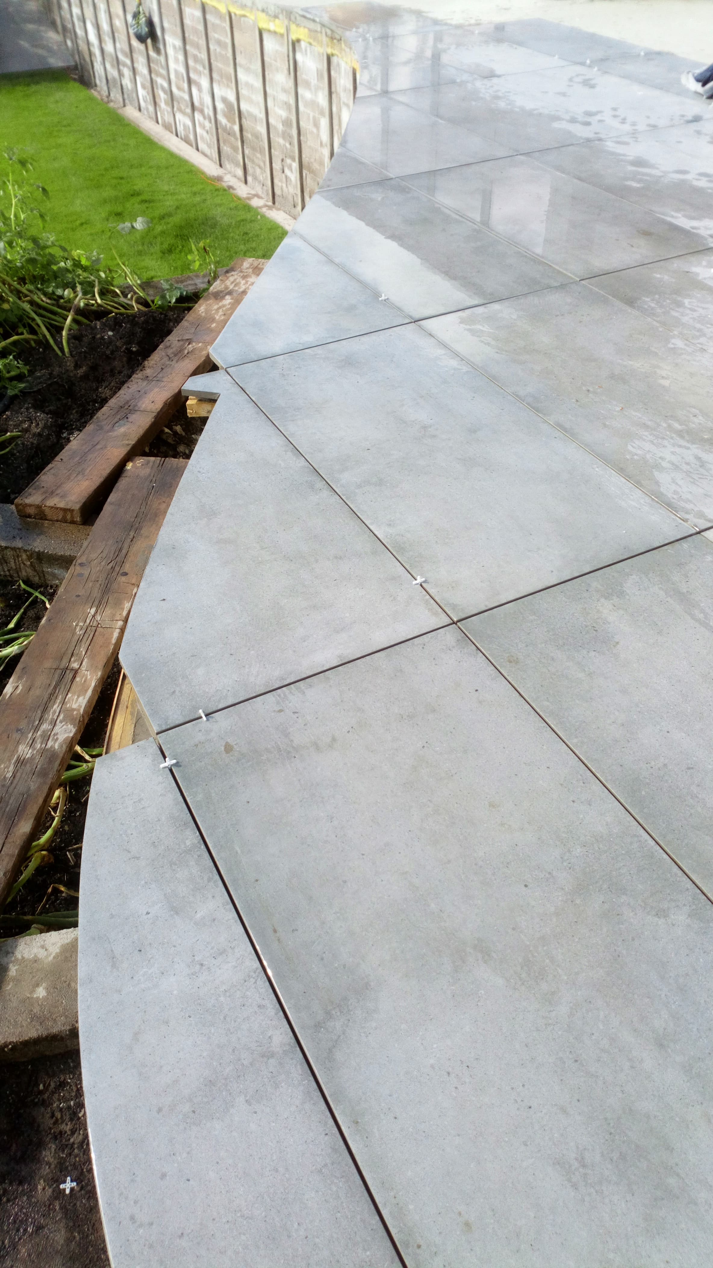Hand-cut curved porcelain slabs following the edge of a planter — the craft shot
