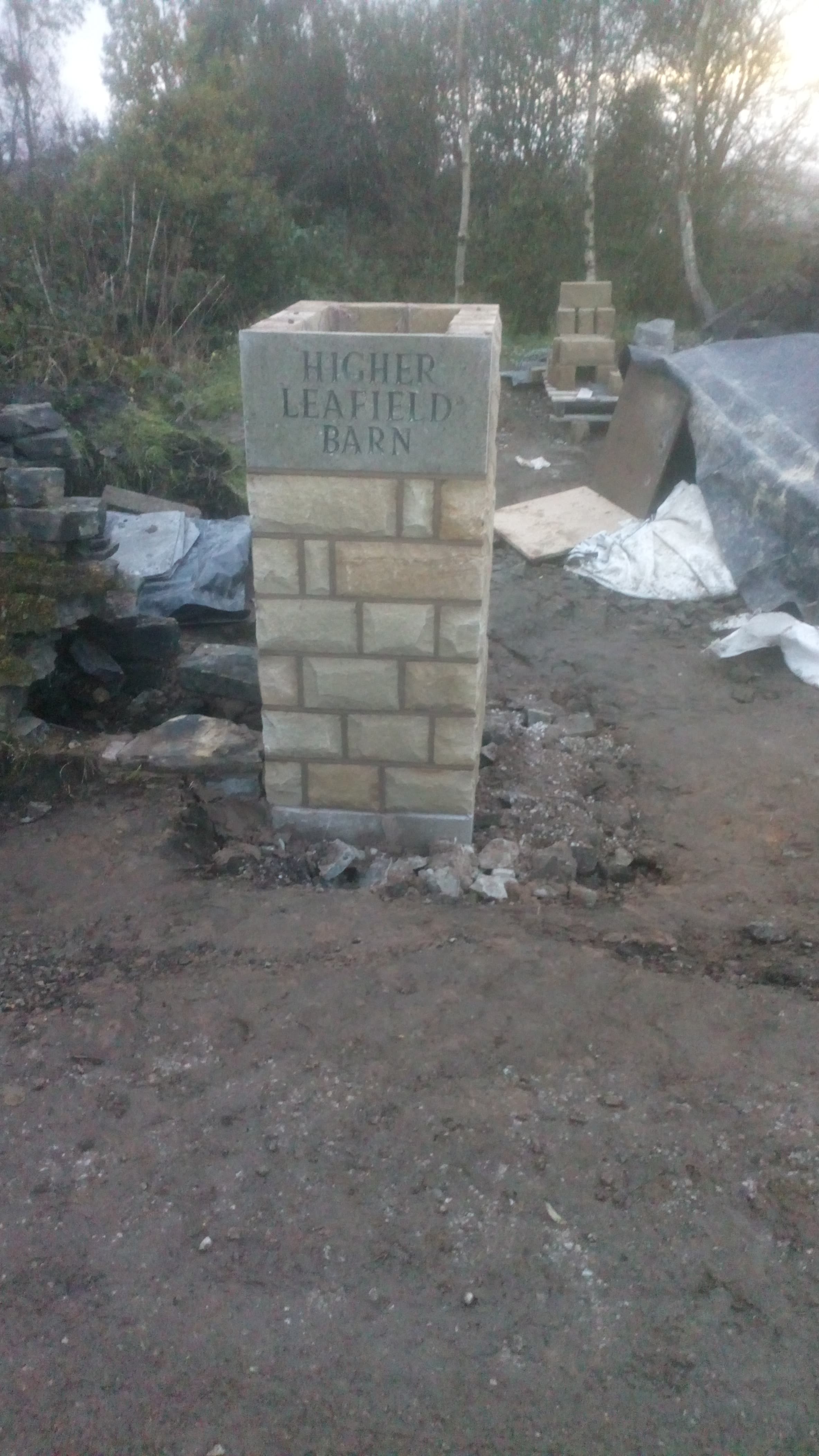 Higher Leafield Barn — first sandstone gatepost mid-build with the carved house-name stone going on top